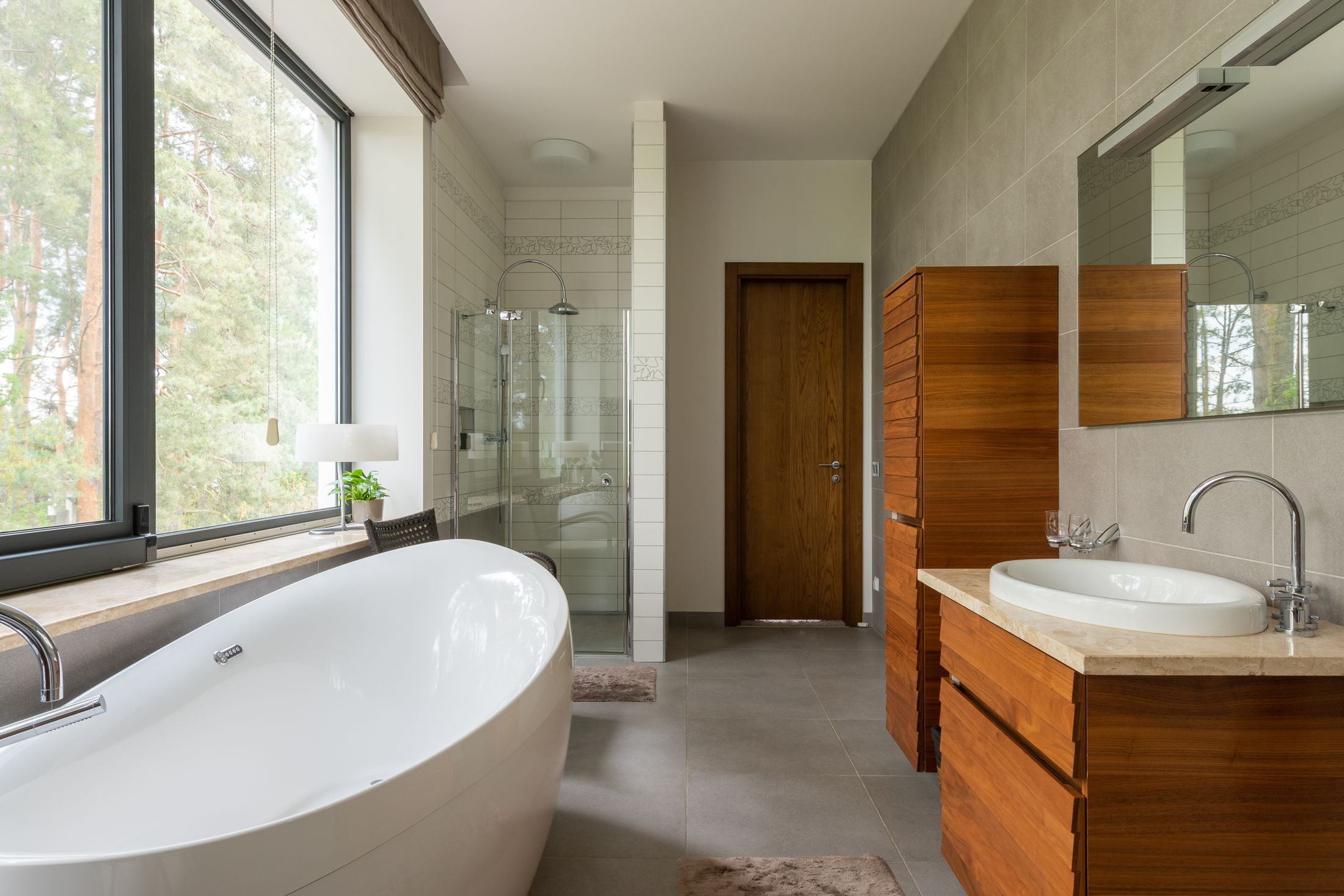 Renovated bathroom with a freestanding tub under a wide window and a timber vanity