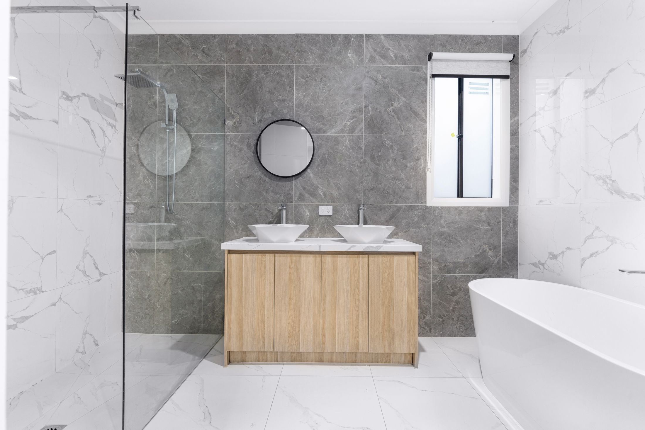 Marble-look bathroom with a frameless shower, freestanding tub and timber vanity